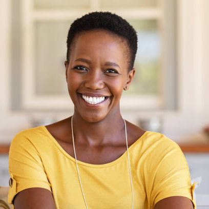 Mature happy woman smiling and looking at camera. Portrait of african american woman in casual clothing and curly short hair relaxing at home.  Portrait of successful black lady with copy space.